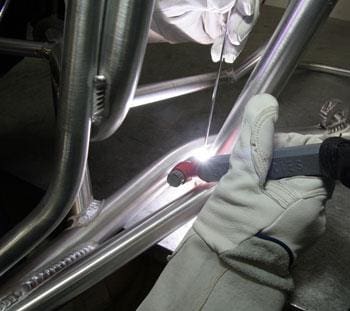 A person welding the bottom of a motorcycle.