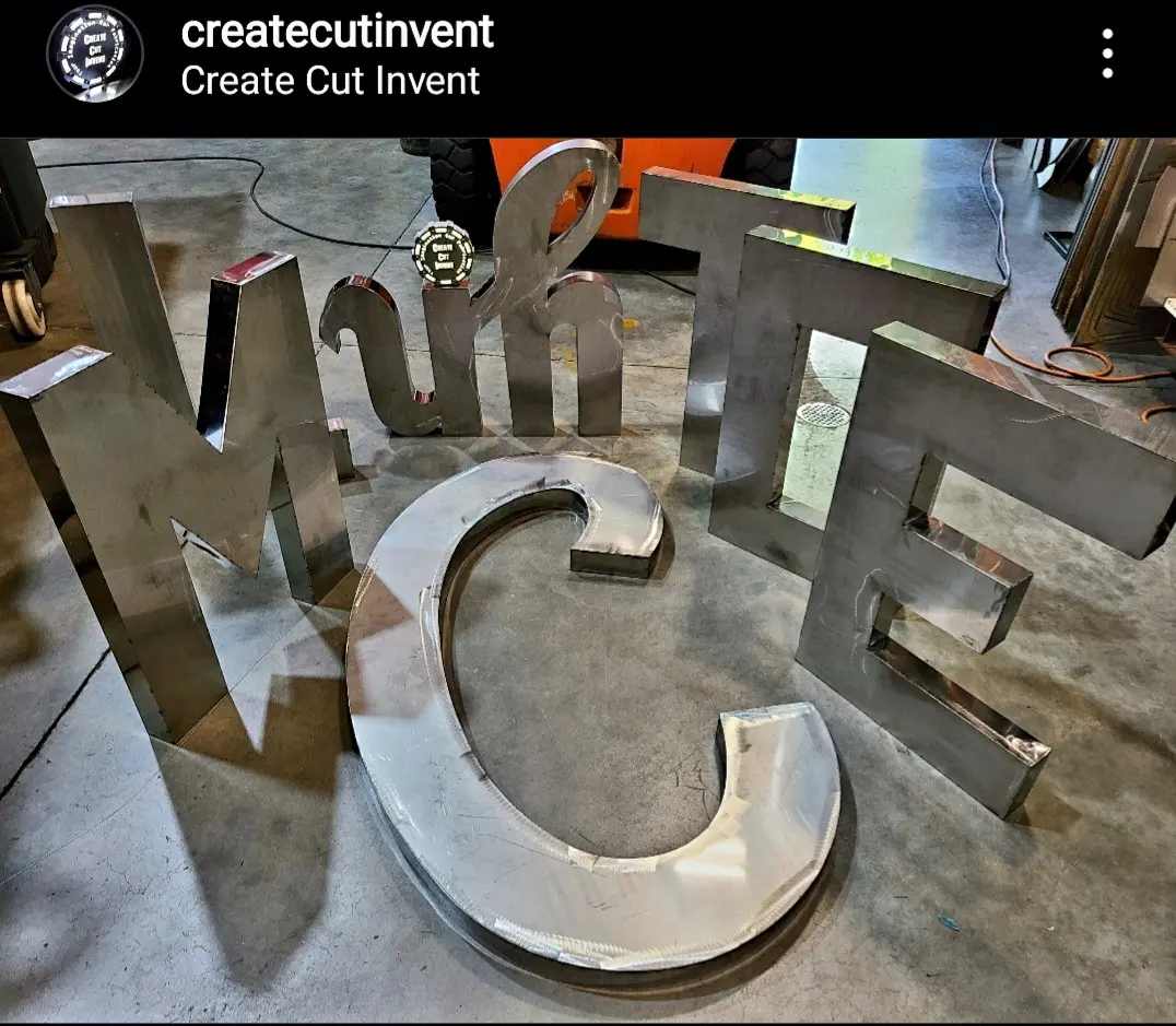 A metal letter sitting on top of concrete.